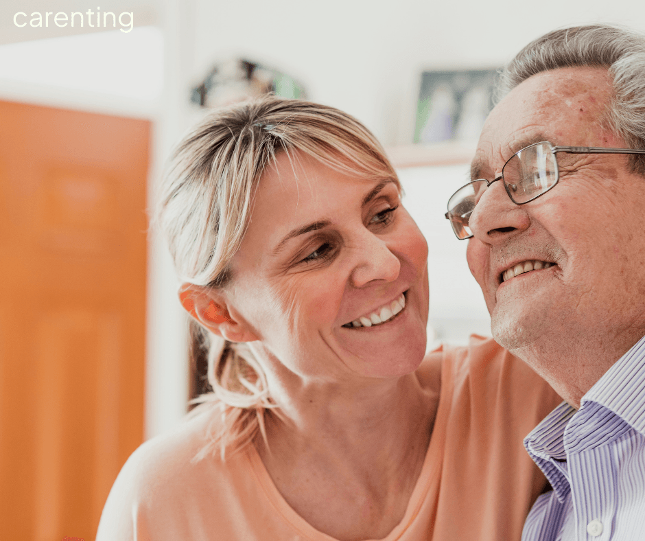 Smiling woman embraces an older man, both looking happy in a cozy, indoor setting. - Home Instead