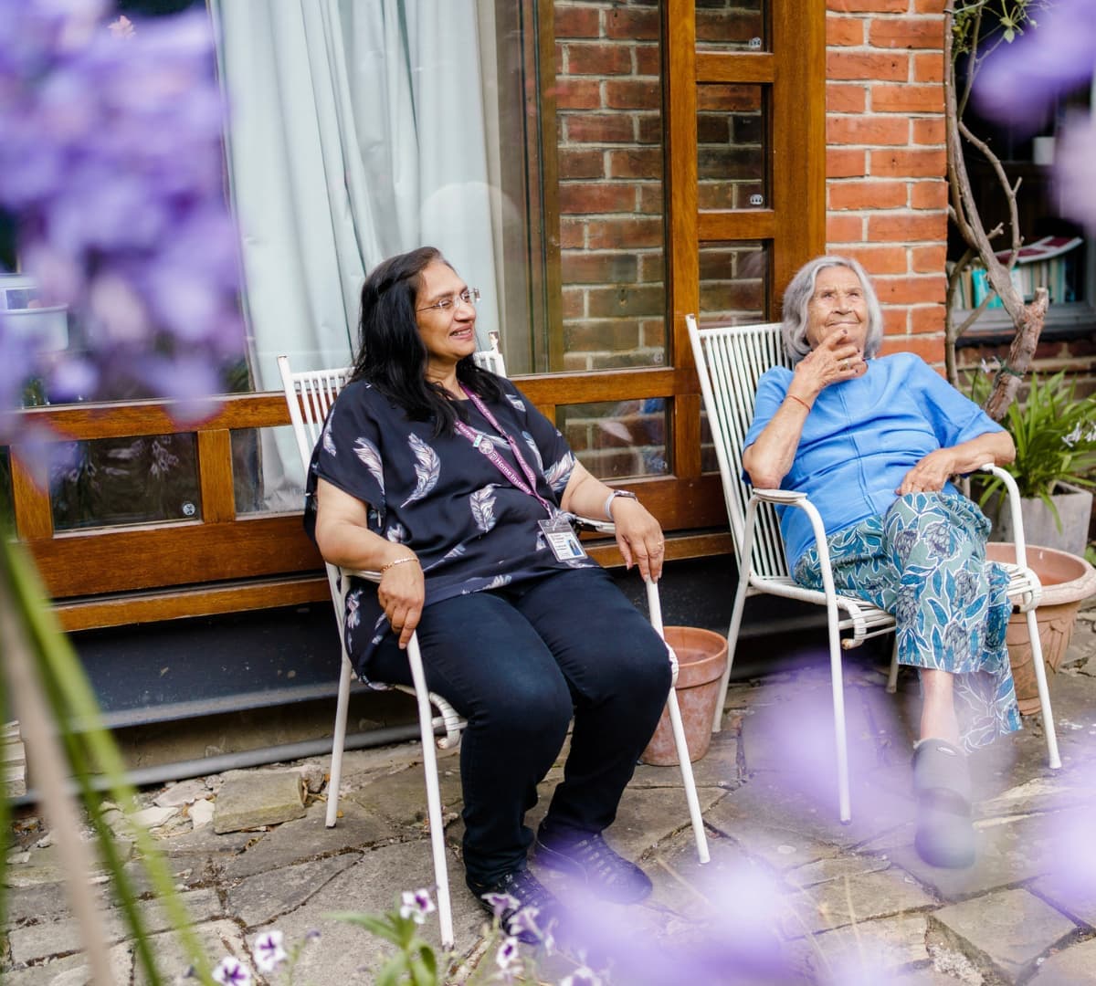 Two womne sitting at the front of the house while chatting