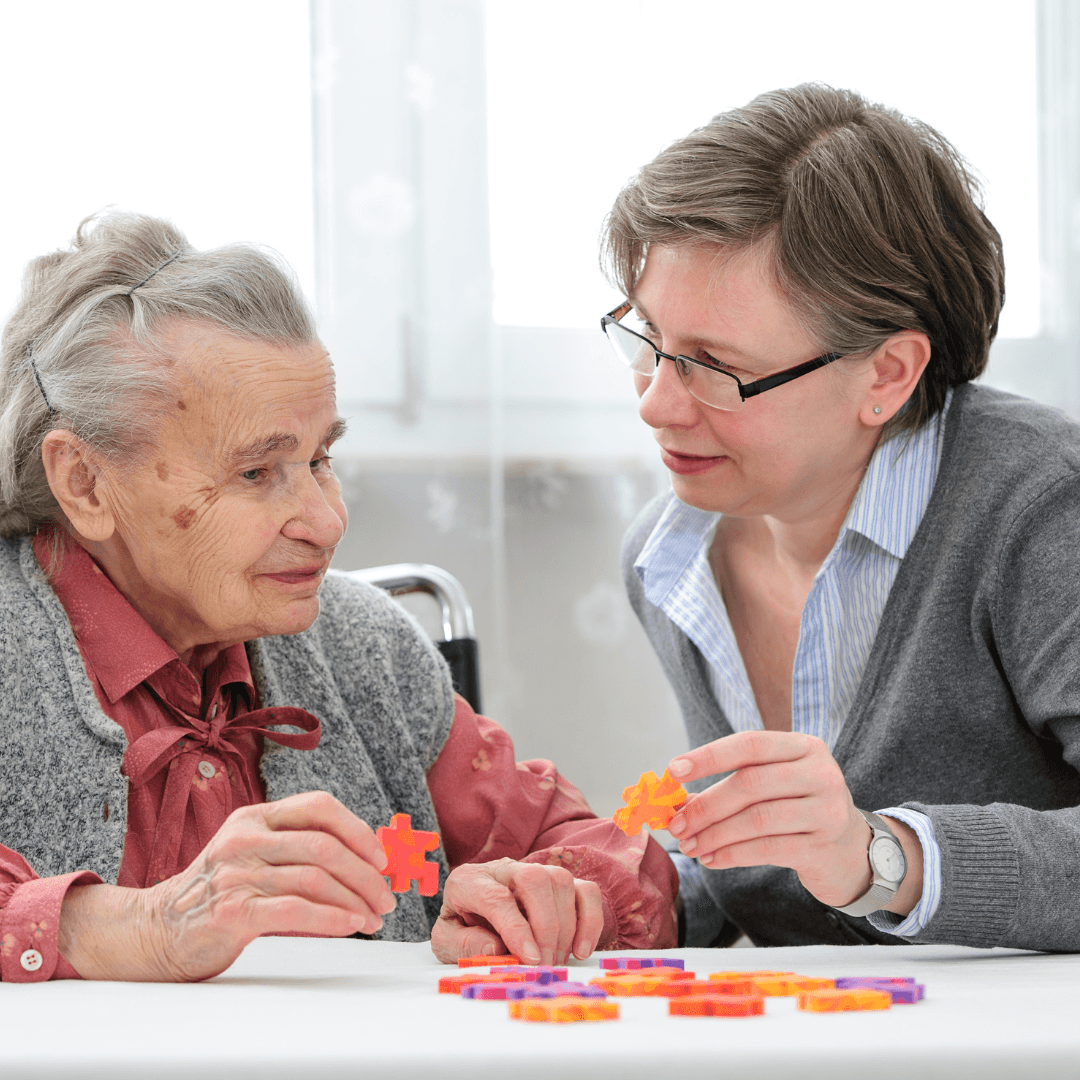 Individual living with dementia playing a puzzle game with a carer