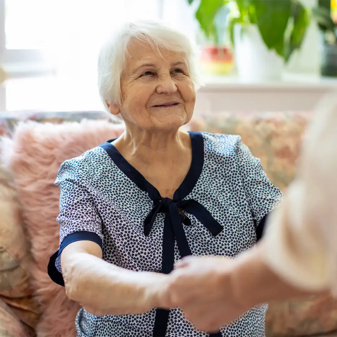 Elderly lady holding hands with her care professional