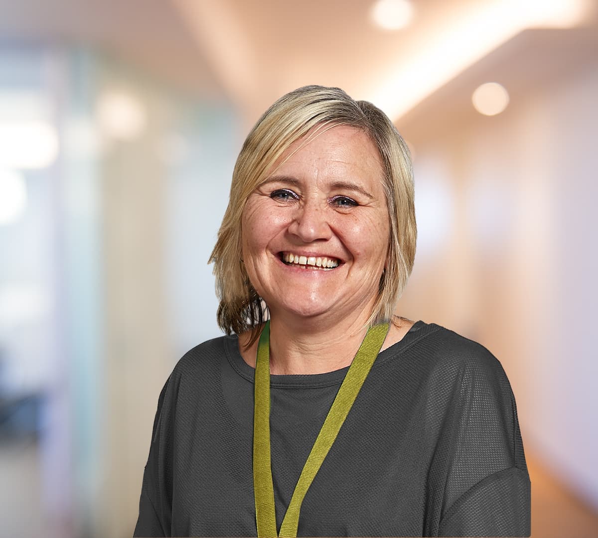 A woman with short blonde hair and wearing green smiling and happy
