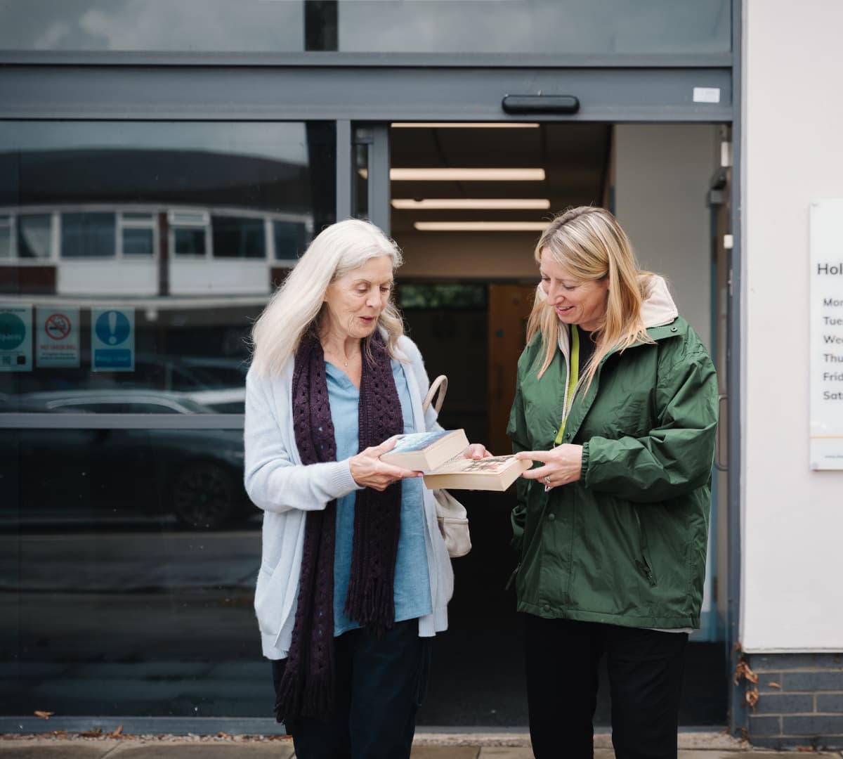 Two women going out o the library while looking at a book