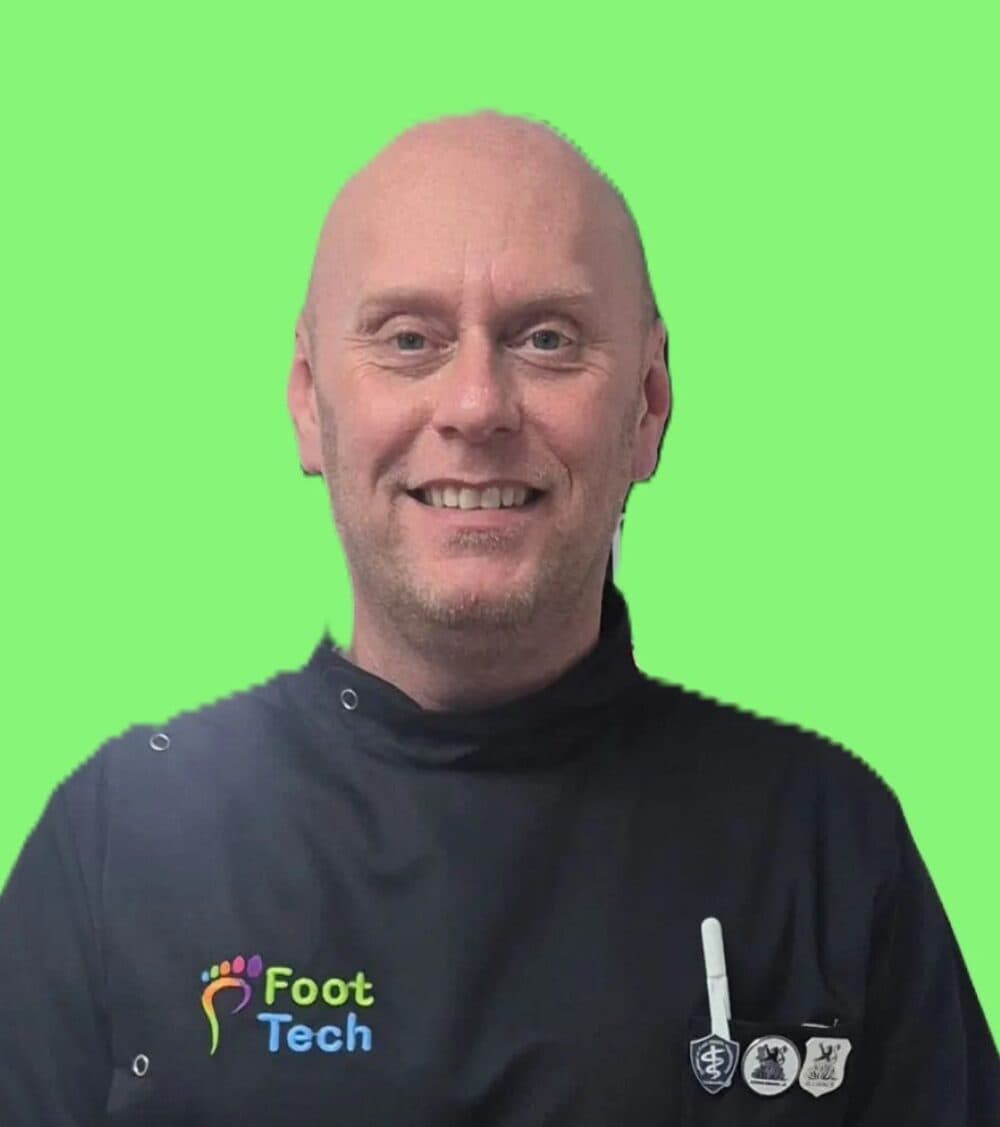 Smiling man in a Foot Tech uniform stands against a bright green background. - Home Instead