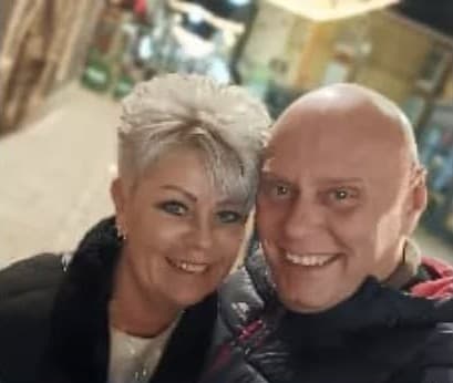 A smiling woman and man pose together for a selfie on a street at night. - Home Instead