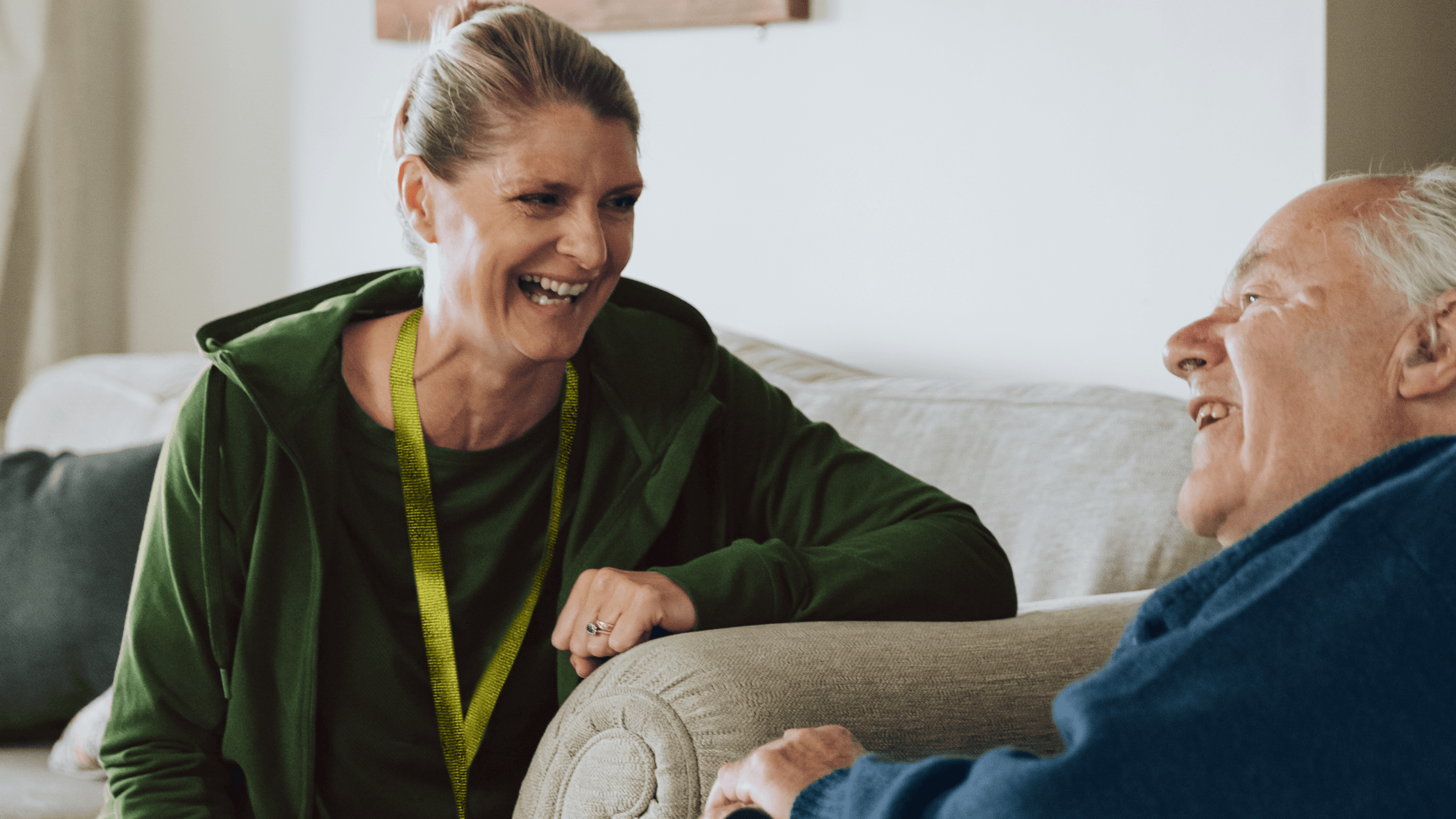 Carer having a chat and laugh on the sofa with a elderly gentleman
