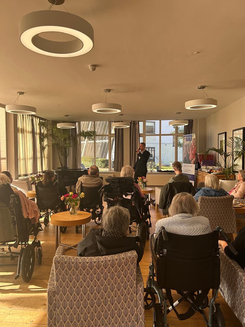 Busy Cafe with elderly visitors enjoying a man singing at the front of the hall.