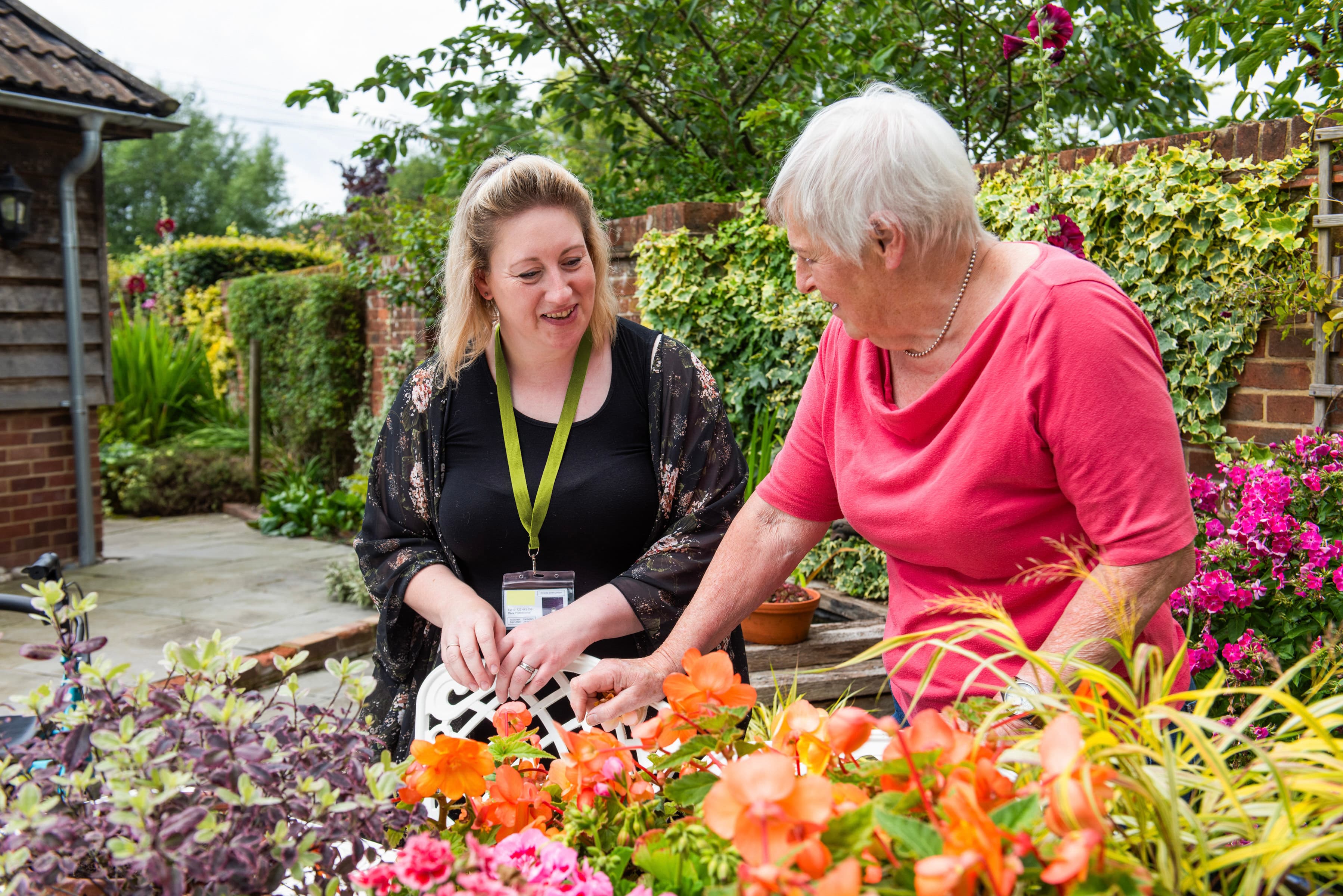 Two women (one older) looking at flowers in a garden