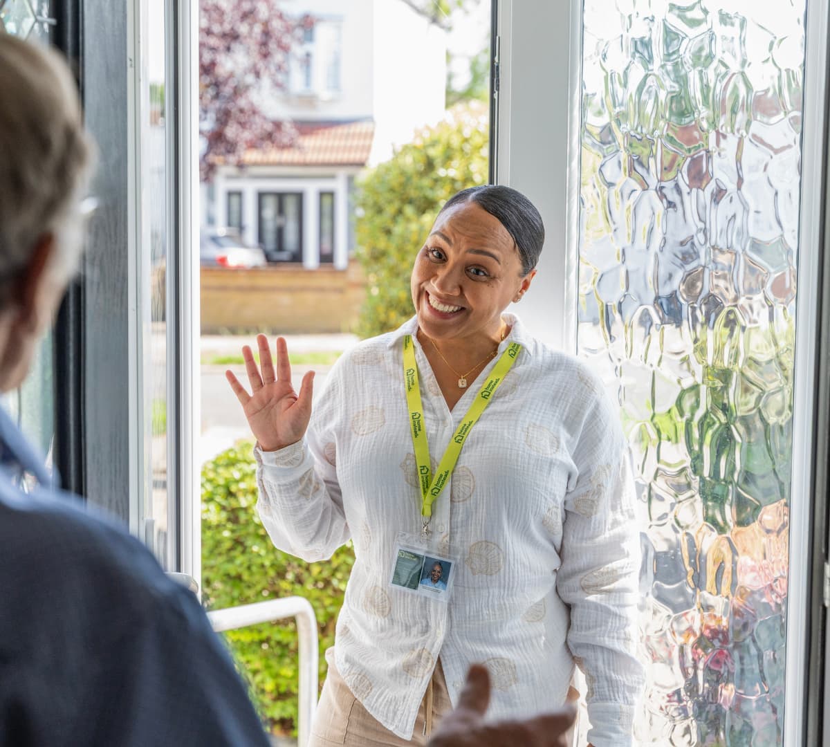 A woman with short hair and wearing jacket smiling and happy with houses at her background