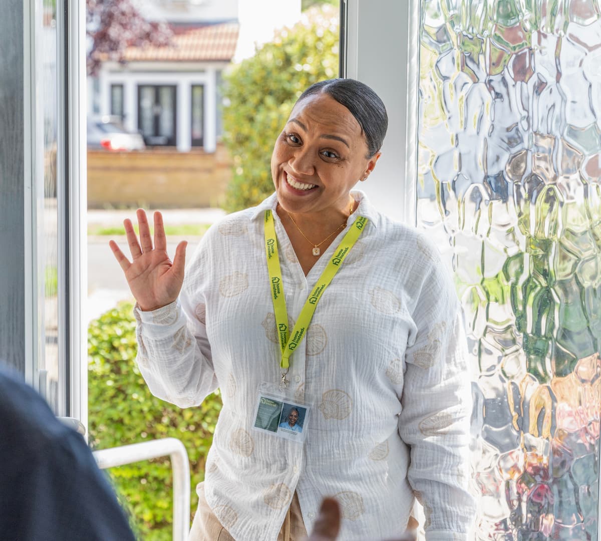 A woman at the door waving and smiling