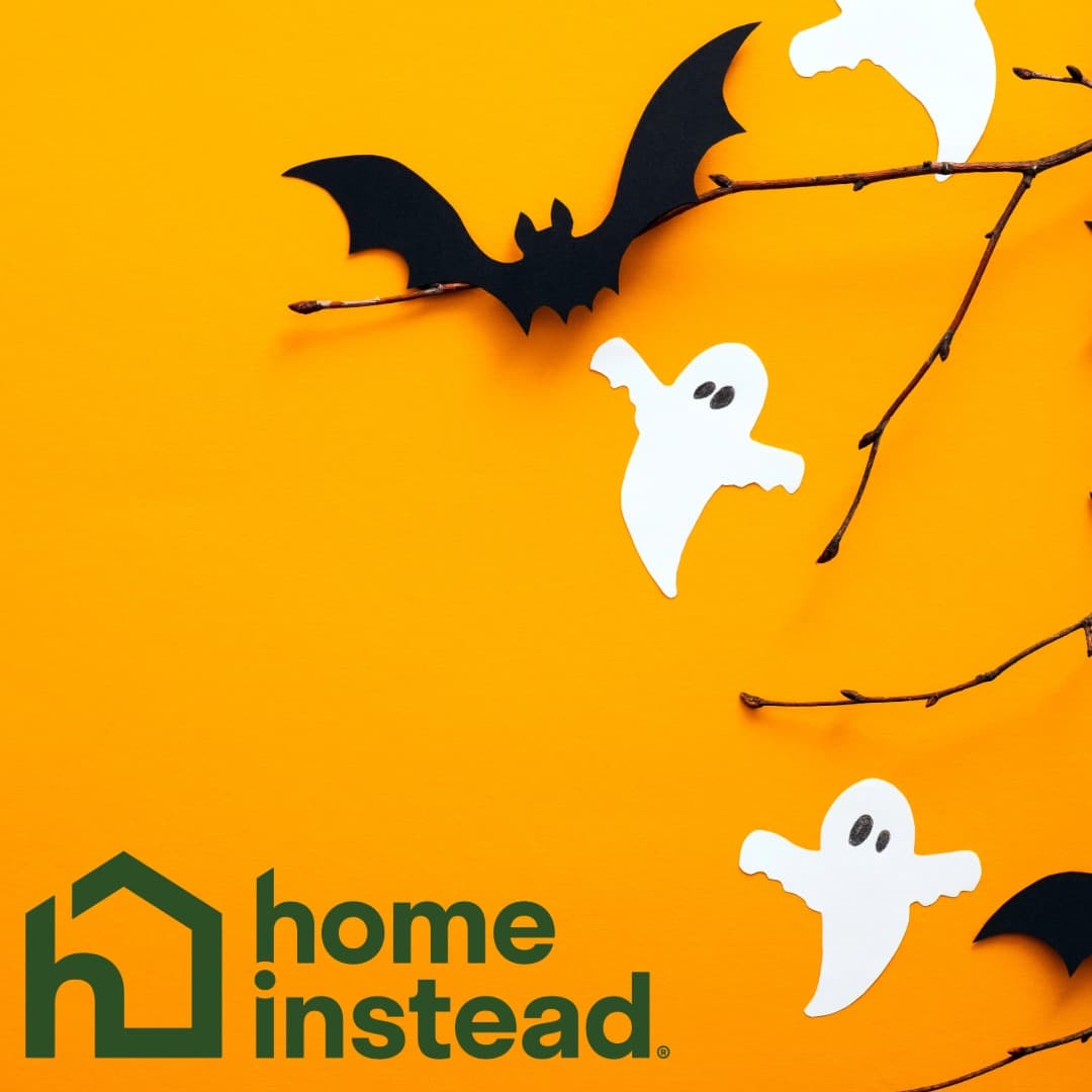 Paper ghosts and a bat on branches with the Home Instead logo on an orange background. - Home Instead