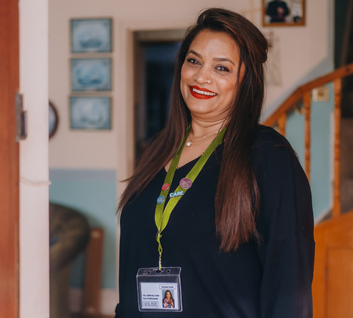 An older female adult with long black hair happy and smiling while standing inside the house