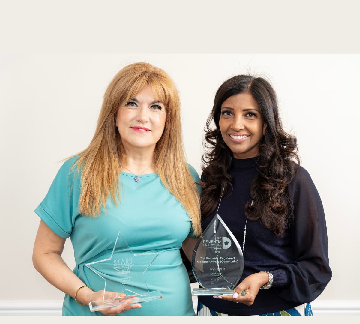Two women smiling while standing and holding an award