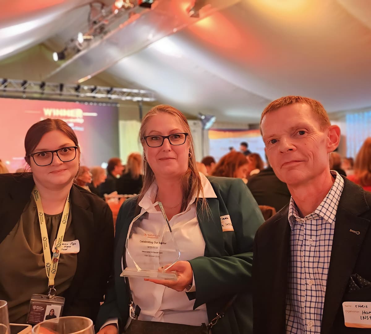 Two women and one man happy and smiling while sitting inside the hall