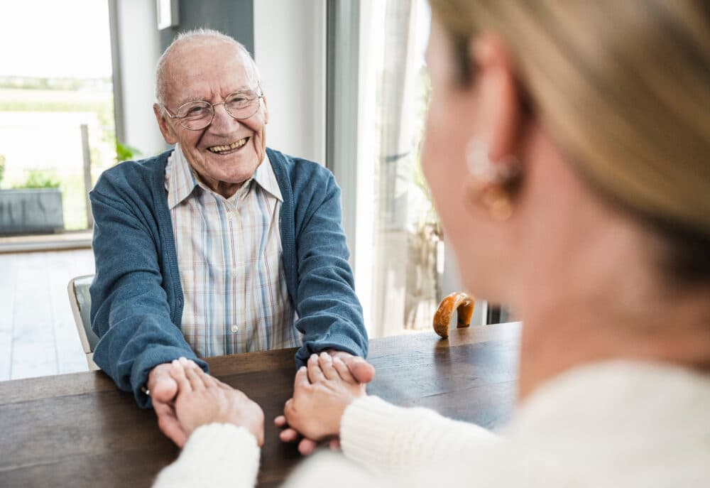 Happy senior man holding hands with daughter at home