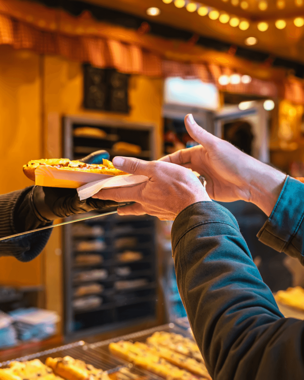 A person receives a slice of pizza from a vendor at an indoor food market. - Home Instead