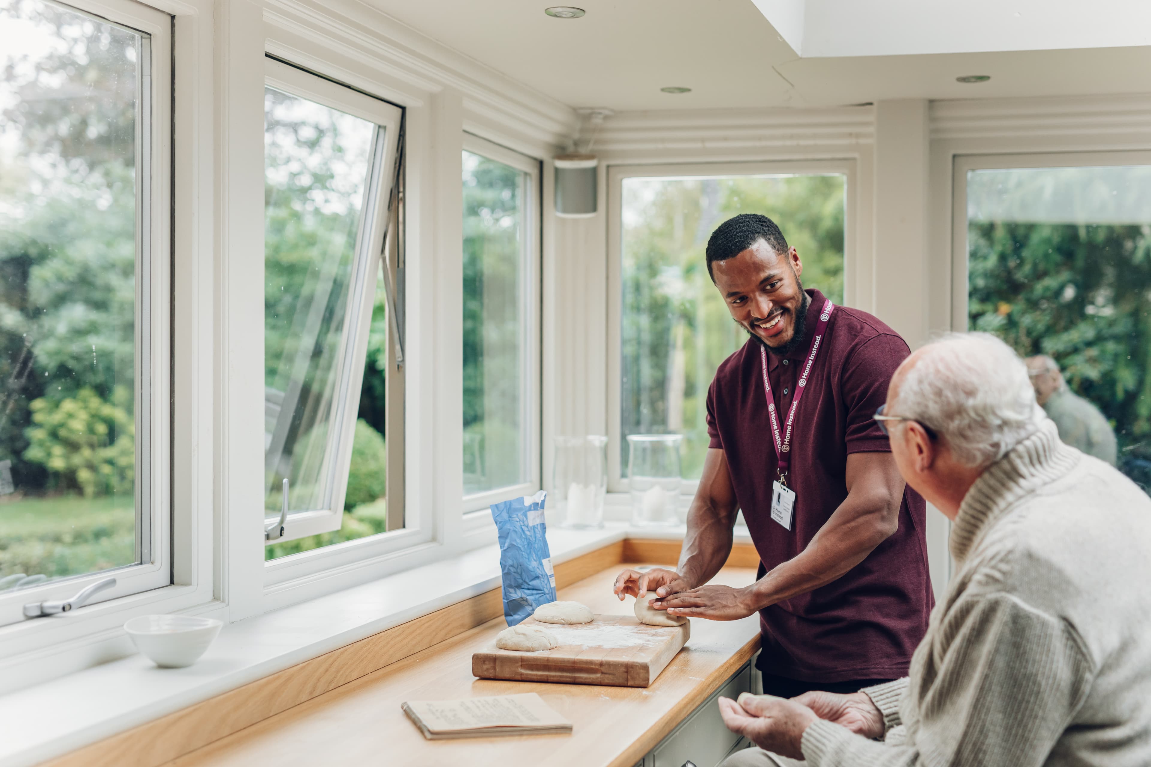 Male Care pro making bread with male client. Both are smiling and enjoying the activity.