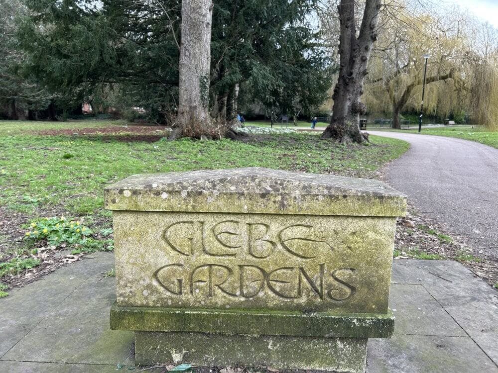 Home Instead picture of entrance to Glebe Gardens, showing a stone plinth with Glebe Gardens written on it and a winding path through trees in the background