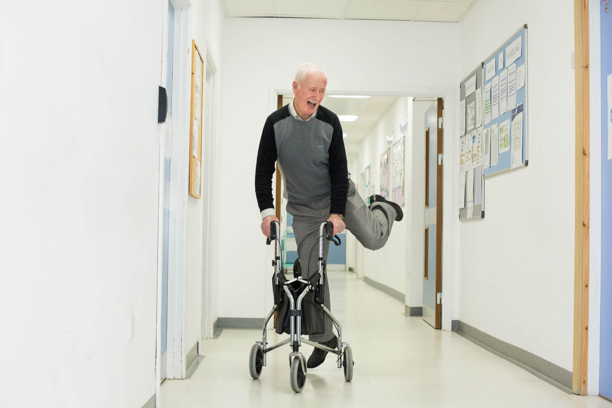 Home Instead client with a walker skipping in a hospital corridor