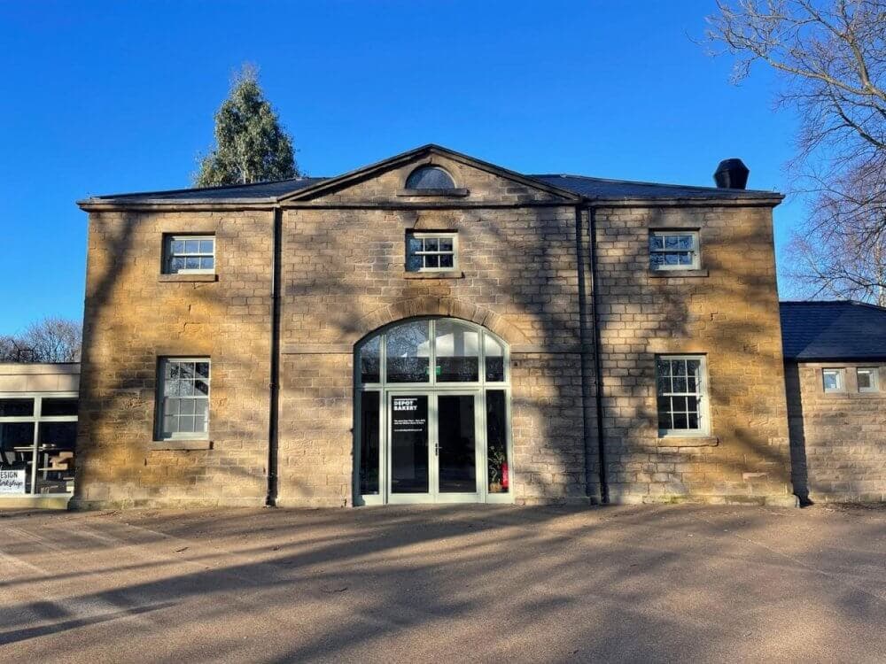 A two-story stone building with large arched windows and a clear blue sky in the background. - Home Instead
