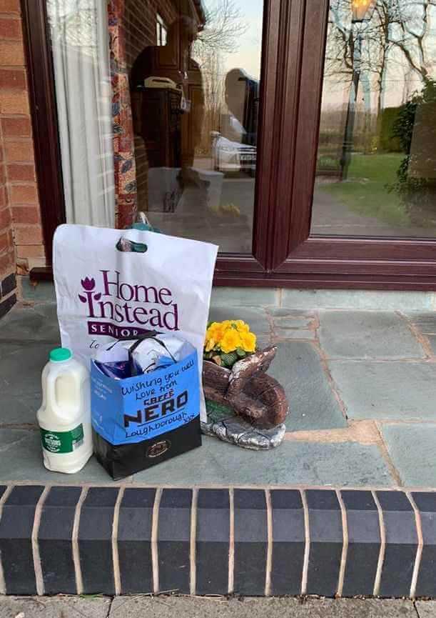 Grocery bag, milk carton, and a yellow flower pot placed on a doorstep in front of a glass door. - Home Instead