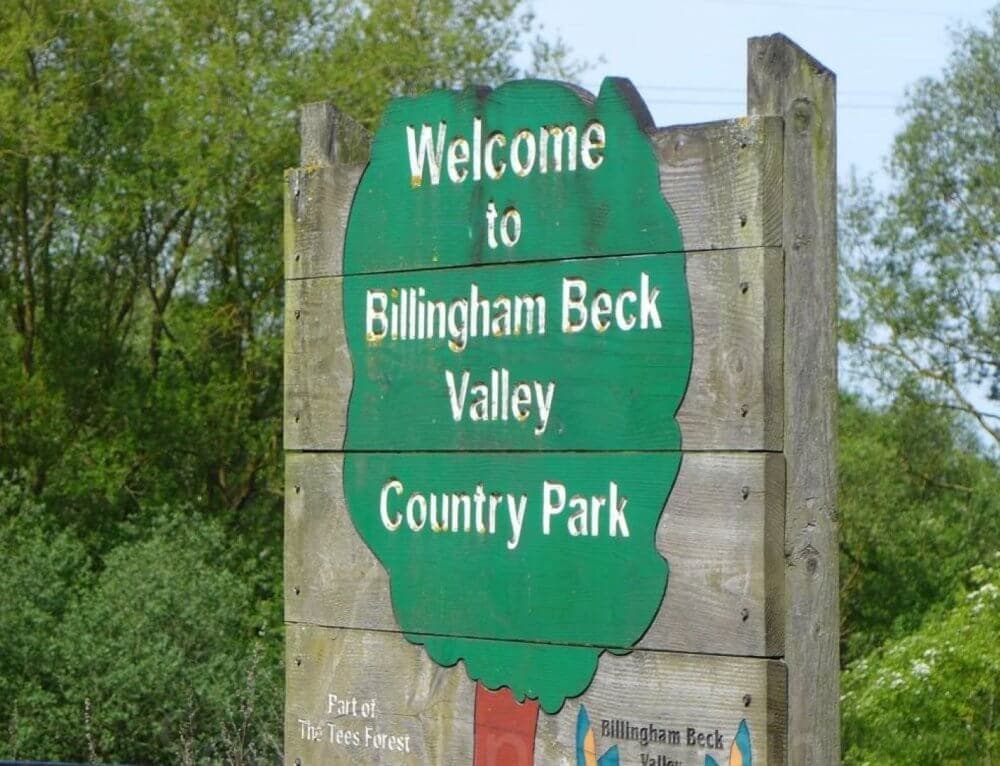Wooden sign reading "Welcome to Billingham Beck Valley Country Park" with trees in the background. - Home Instead