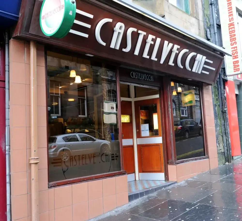 Castelvecchi Fish & Chips - Facade of Castelvecchi restaurant with large windows and wooden door on a rainy street. - Home Instead Renfrewshire and Barrhead home care services