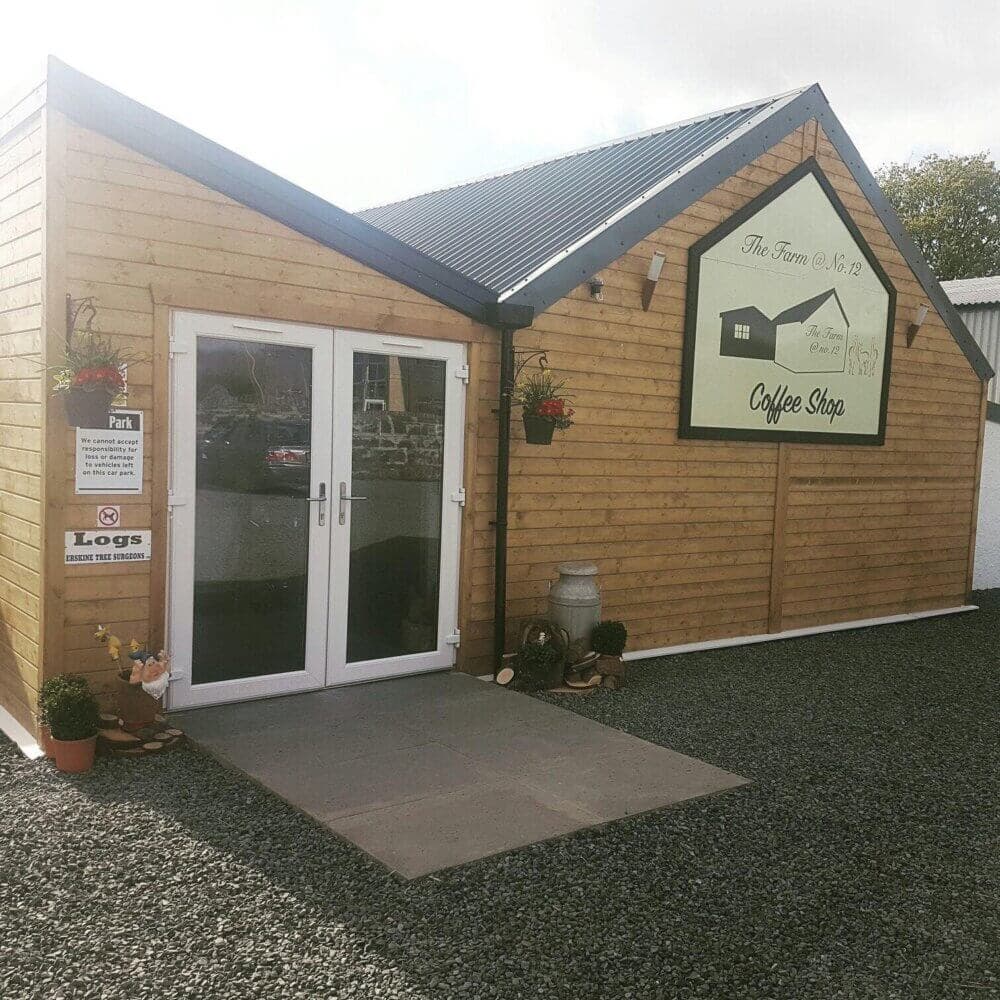 Small wooden coffee shop exterior with glass doors and a sign reading "The Farm Coffee Shop" with plants surrounding the entrance. - Home Instead