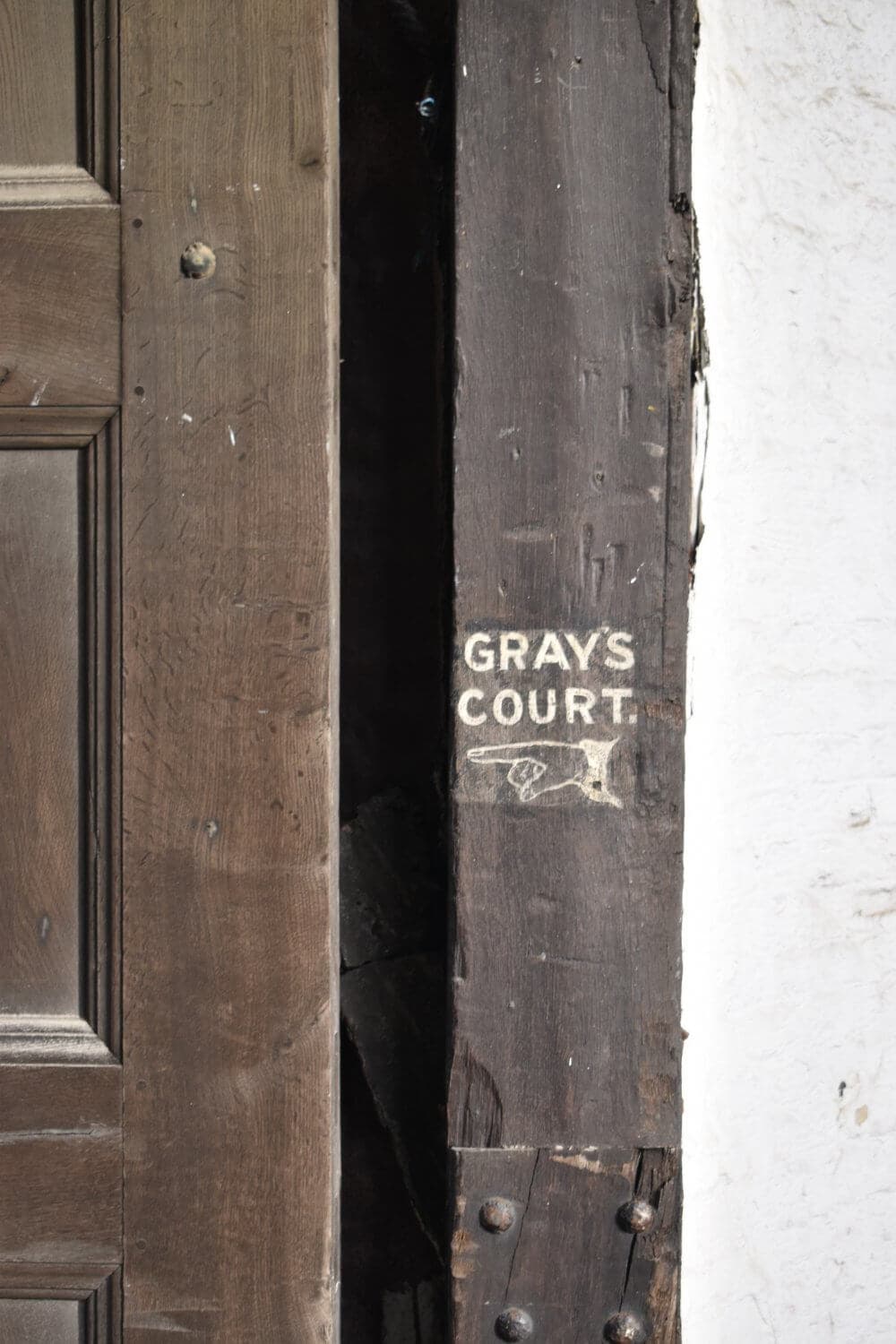 A weathered wooden door with a "Gray's Court" sign and an etched arrow pointing right. - Home Instead
