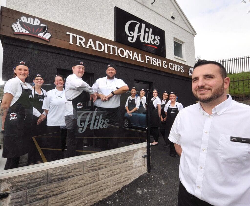 A team of staff stands outside Hiks Traditional Fish & Chips restaurant, with one staff member in the foreground. - Home Instead