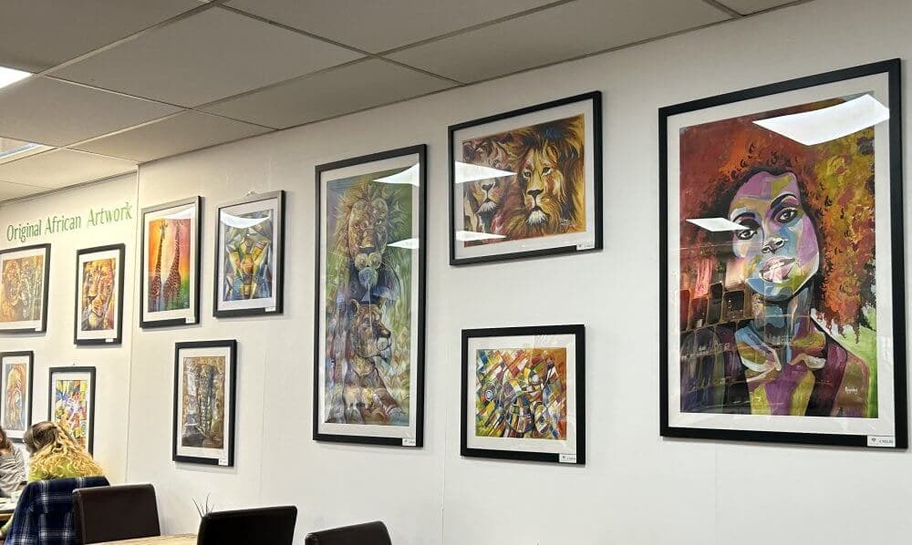 Home Instead Basingstoke picture of the gallery wall at Vermillion, Chineham, showing a range of framed African artwork, featuring portraits and vibrant, colourful scenes.