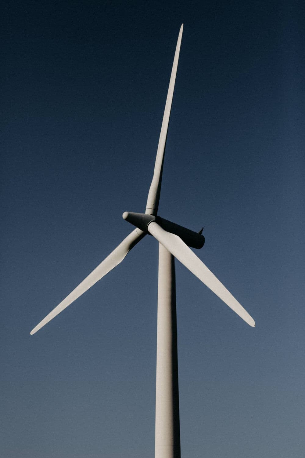 A large white wind turbine with three blades against a clear blue sky. - Home Instead