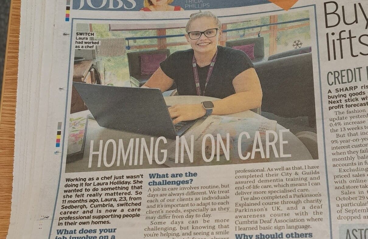 Smiling woman with glasses using a laptop, accompanied by a newspaper article titled "Homing In on Care. - Home Instead