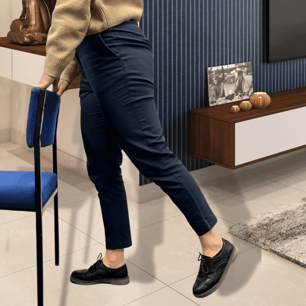 Person in black shoes and navy pants moving a blue chair in a modern living room. - Home Instead