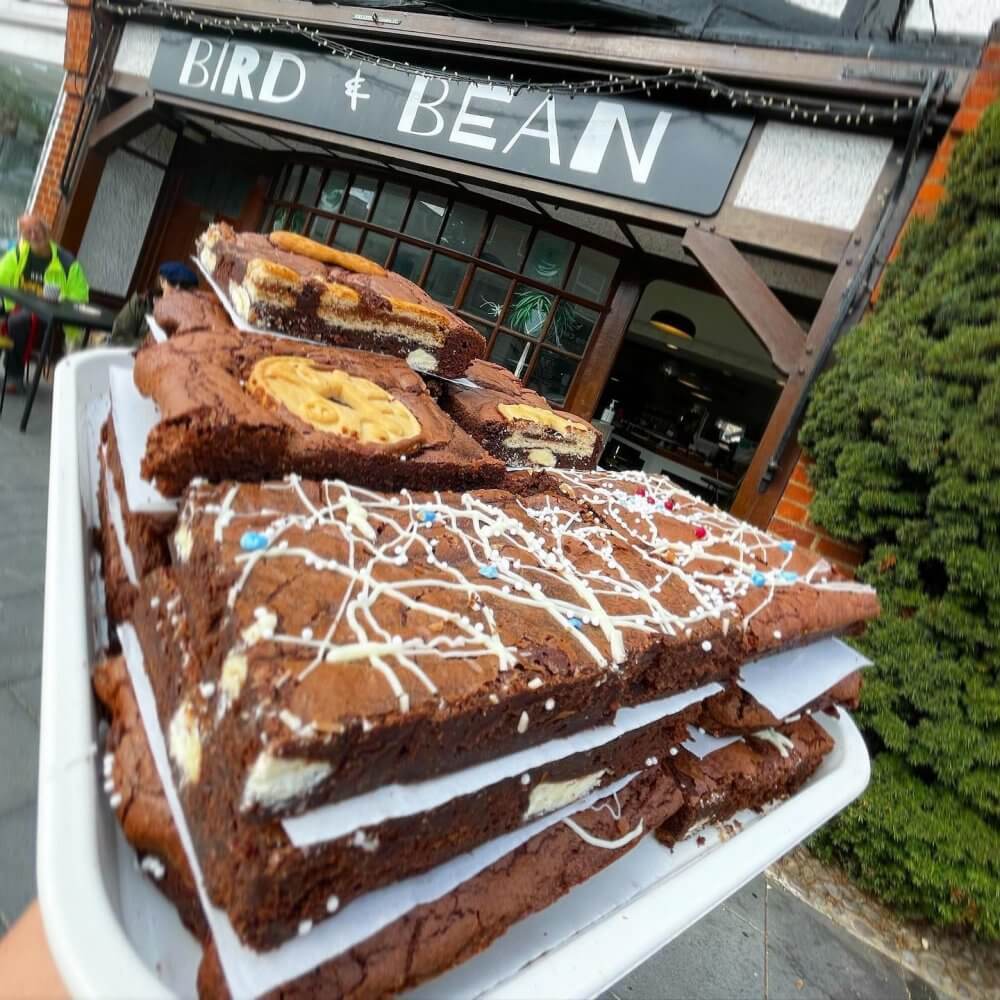 A tray of large, decorated brownies in front of a café named Bird & Bean. - Home Instead