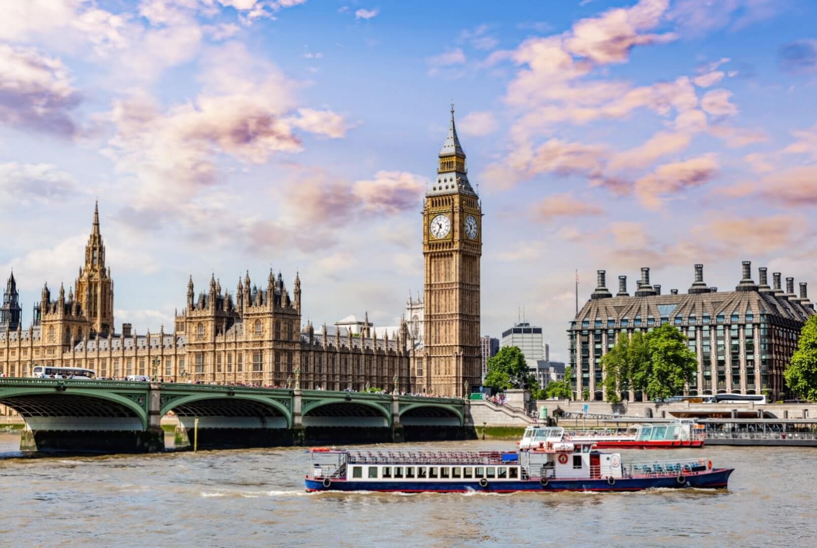 View of Big Ben, Westminster Bridge, and boats on the River Thames with a backdrop of partly cloudy sky in London. - Home Instead