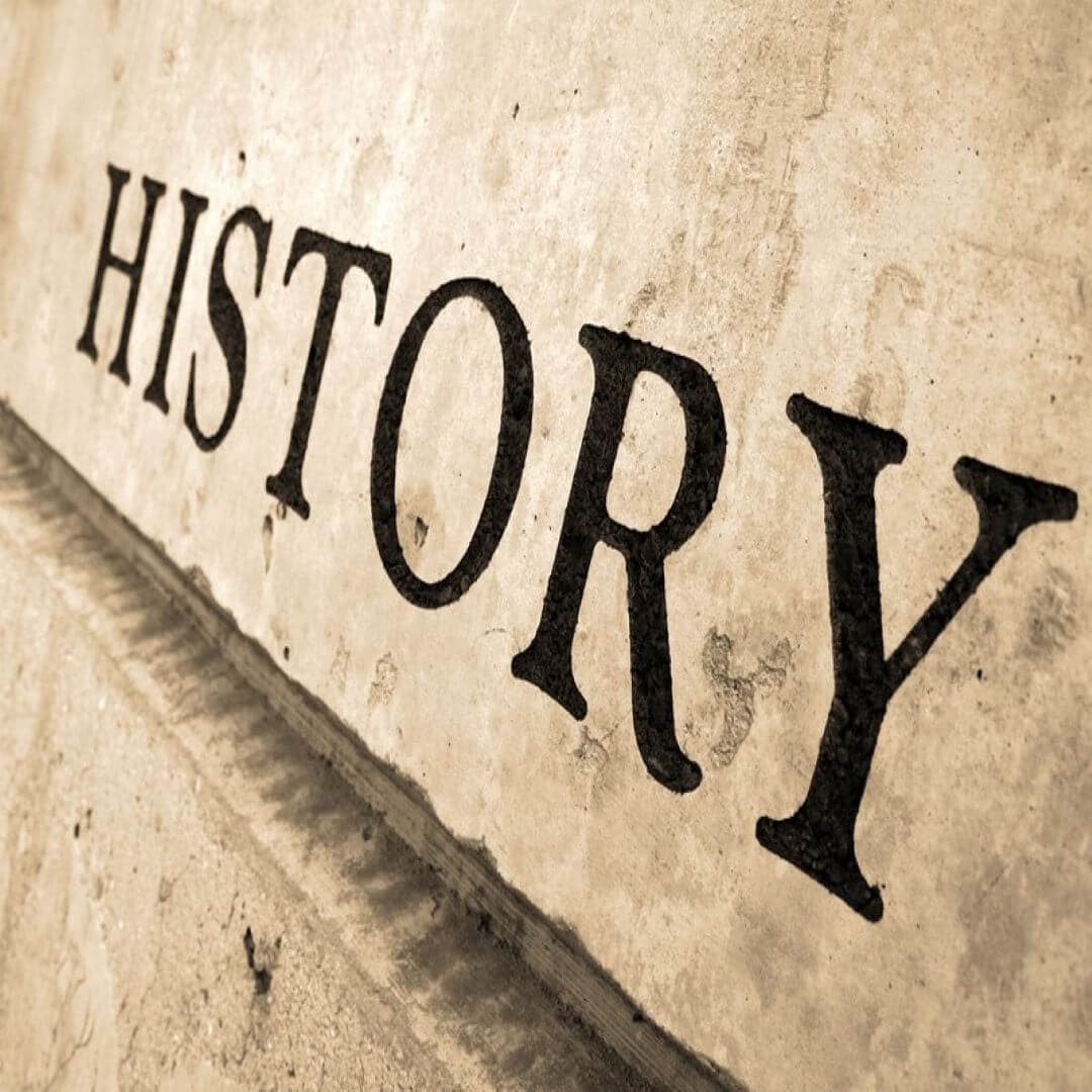 Sepia-toned close-up of the word "HISTORY" etched into a surface, featuring a vintage, textured background. - Home Instead