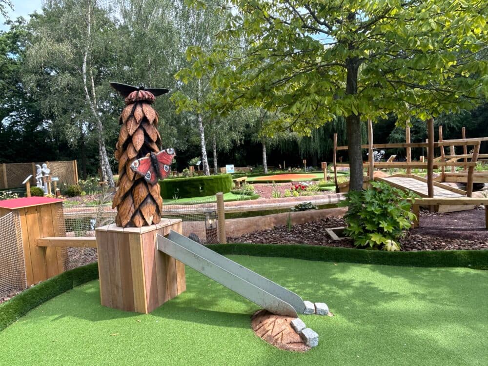 View across the crazy golf course at Sherfield on Loddon Garden Centre showing a hole with an up ramp and plant sculpture above, and other holes on the course in the background