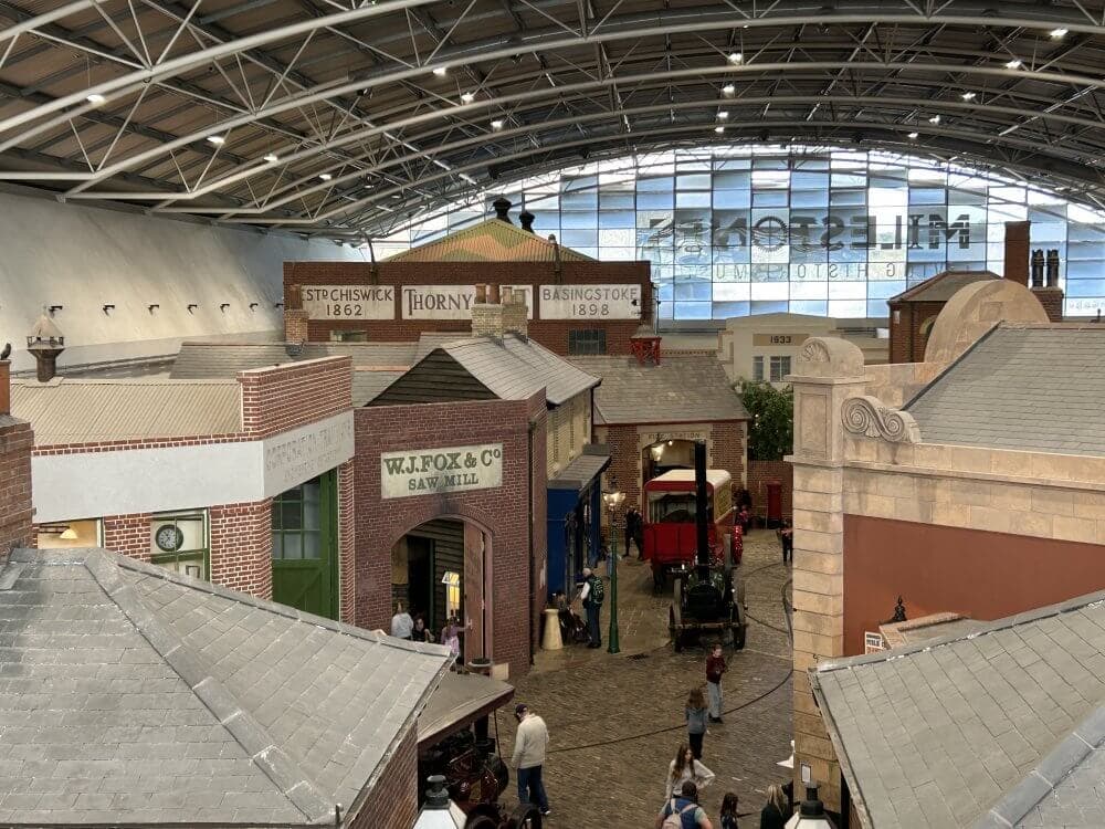 Home Instead Basingstoke picture of Milestones Museum in Basingstoke, displaying historical buildings, people walking, and a vintage street scene under a large, curved roof