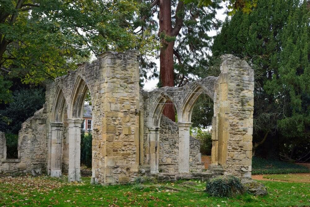 Ancient stone ruins with arched windows and doorways surrounded by greenery and trees. - Home Instead