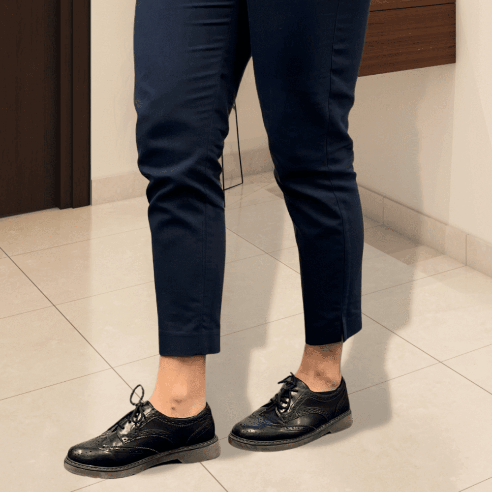 Person in navy pants and black dress shoes standing on a tile floor in an indoor setting. - Home Instead