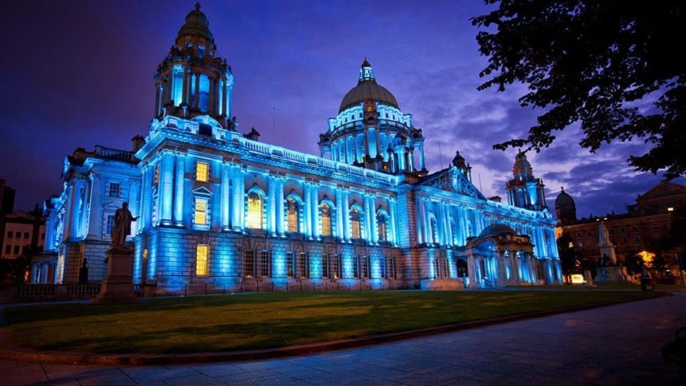 Illuminated building with domes and towers, lit with blue lights against a dark evening sky, featuring classical architecture. - Home Instead