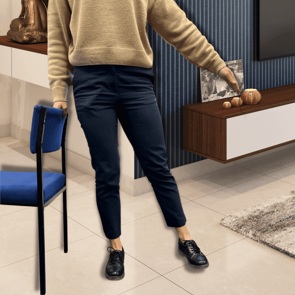 Person in casual clothing holding a blue chair in a modern living room. A cabinet and decorative items are visible. - Home Instead