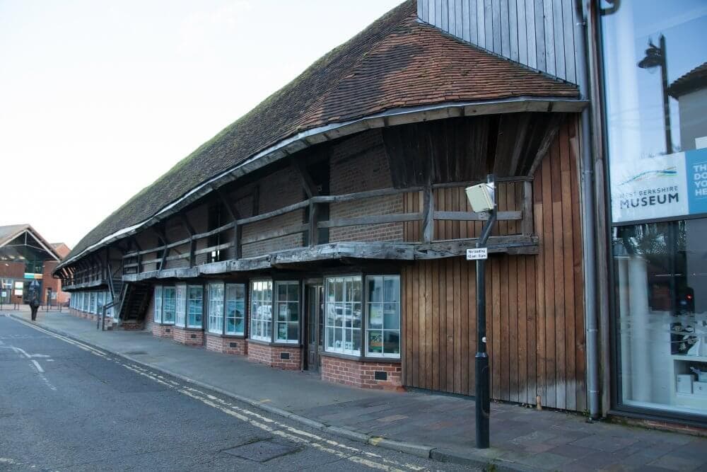 Street view of the exterior of the Bourne Hall Museum, featuring wooden beams and glass windows. - Home Instead