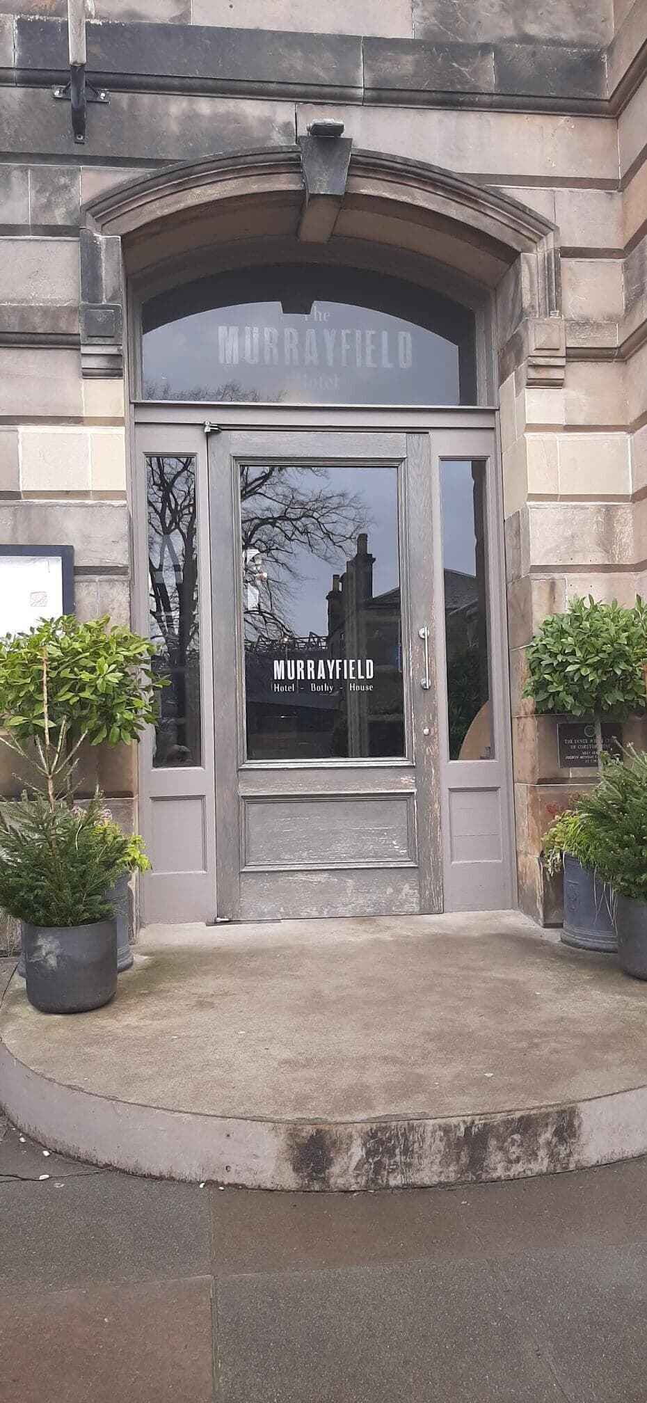 Entrance to The Murrayfield bar and kitchen with potted plants on each side. - Home Instead