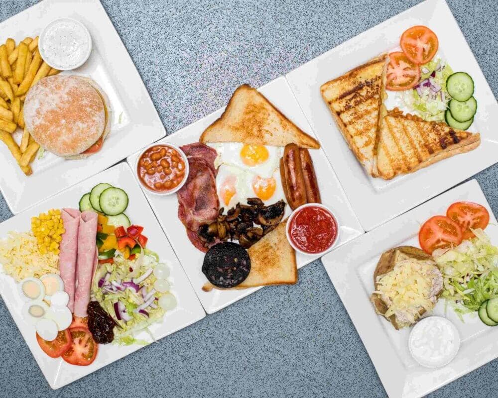 Plates of various meals including a burger, English breakfast, salads, toast with toppings, and a sandwich. - Home Instead