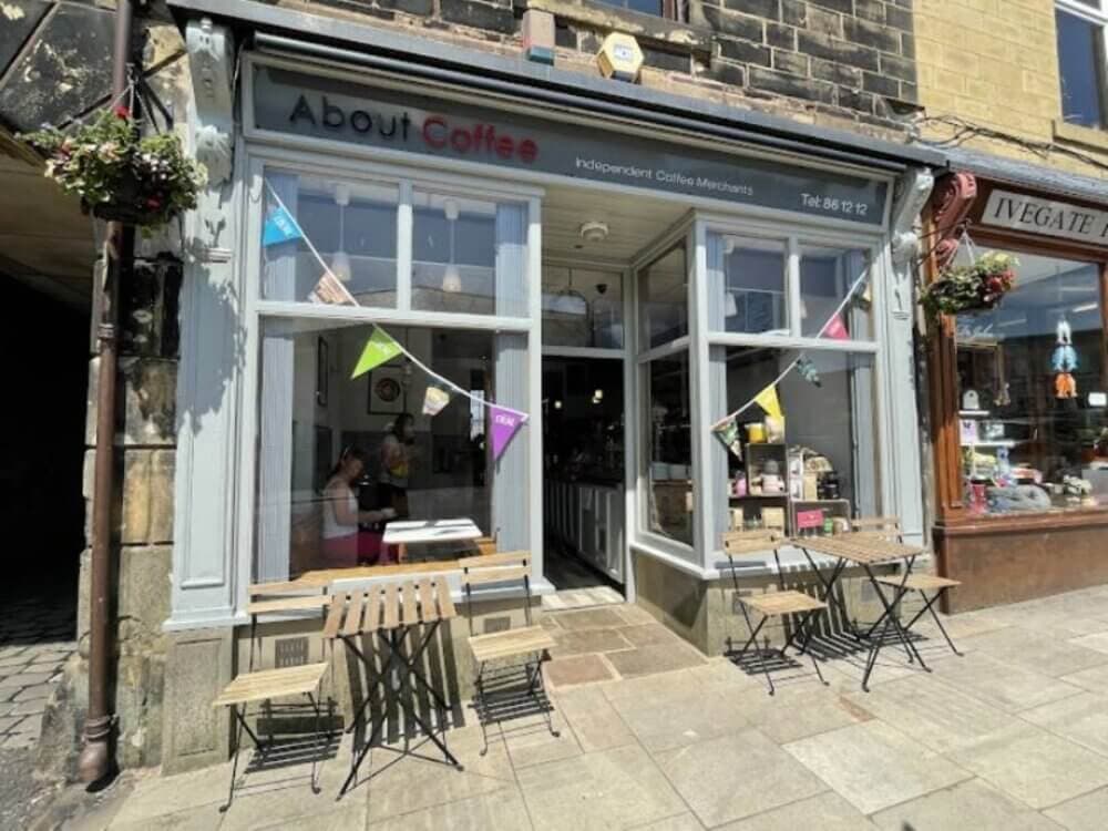 A quaint café with outdoor seating and colorful bunting, nestled between stone buildings on a sunny day. - Home Instead