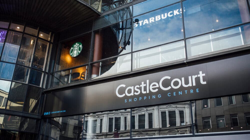 CastleCourt Shopping Centre's glass façade with Starbucks logo and signs visible, reflecting surrounding buildings. - Home Instead