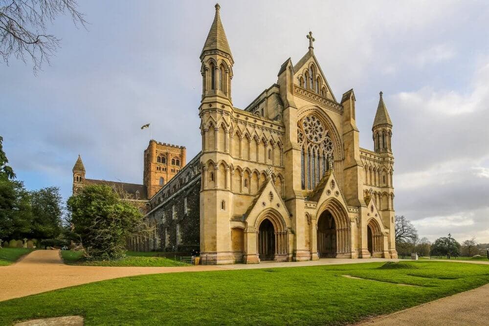 Exterior view of a Gothic-style cathedral with tall spires, arched doorways, and a large rose window, set against a clear sky. - Home Instead