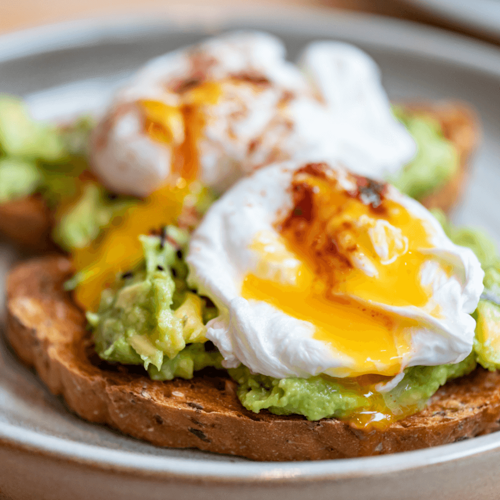 Two poached eggs with runny yolks on avocado toast. - Home Instead
