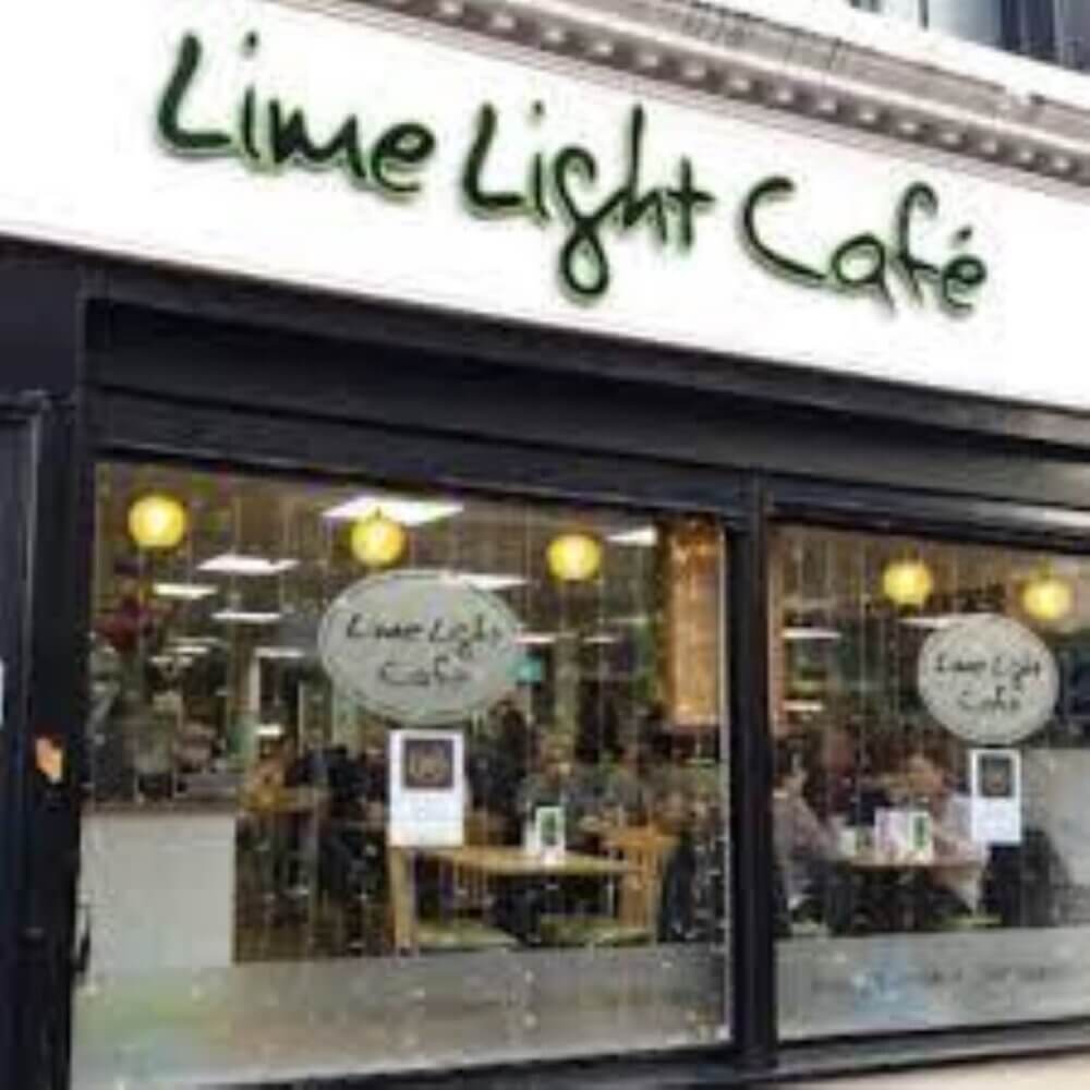 Exterior view of Lime Light Café with a large window displaying the interior seating area and green signage above. - Home Instead